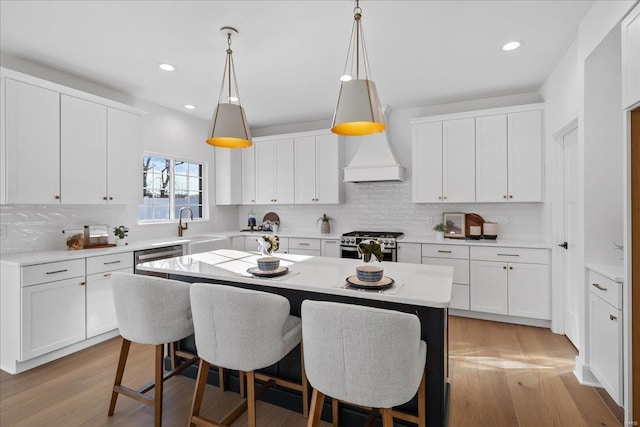 kitchen featuring light wood finished floors, a breakfast bar area, stainless steel appliances, and light countertops