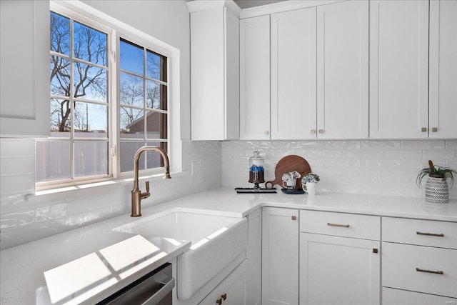 kitchen featuring a sink, white cabinets, light countertops, stainless steel dishwasher, and tasteful backsplash