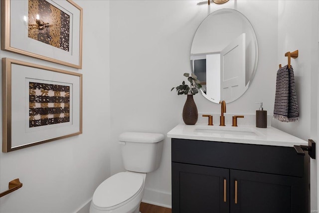 half bath featuring baseboards, vanity, and toilet