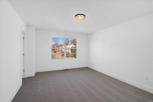 spare room featuring carpet floors, visible vents, and baseboards