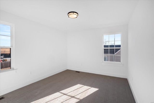 unfurnished room featuring dark carpet, visible vents, and baseboards