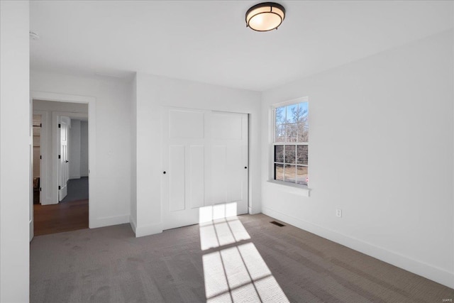 unfurnished bedroom featuring a closet, carpet flooring, visible vents, and baseboards