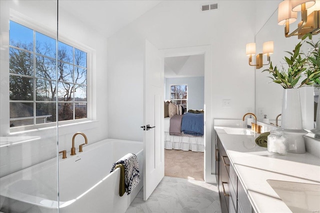 bathroom with double vanity, visible vents, a freestanding bath, connected bathroom, and a sink