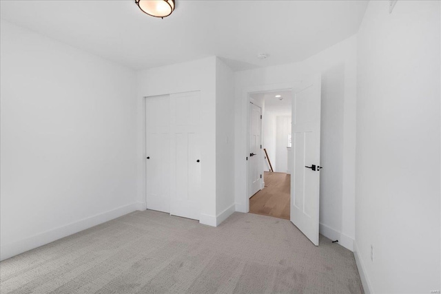 unfurnished bedroom featuring carpet, baseboards, and a closet