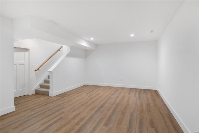 finished basement featuring light wood-style flooring, stairway, baseboards, and recessed lighting