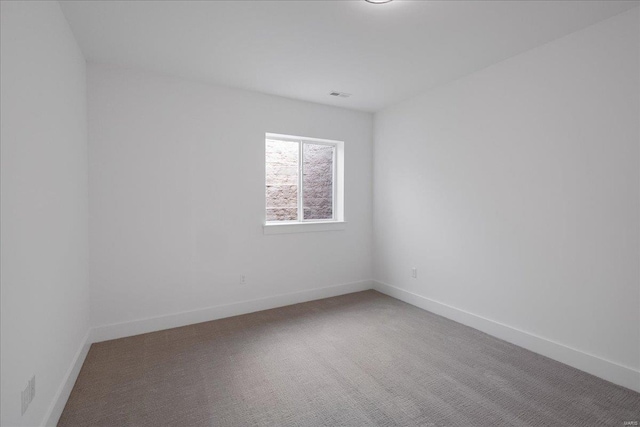 empty room featuring carpet floors, visible vents, and baseboards