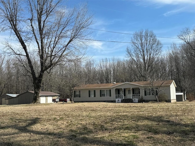 view of front facade featuring a porch, a front lawn, a detached garage, and an outdoor structure