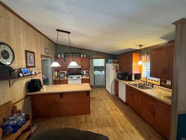 kitchen with light wood-style flooring, a peninsula, white appliances, a sink, and vaulted ceiling