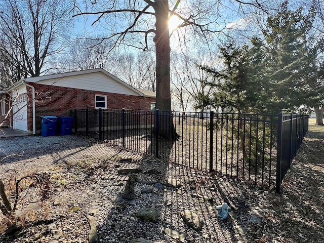 exterior space with a garage, brick siding, and fence