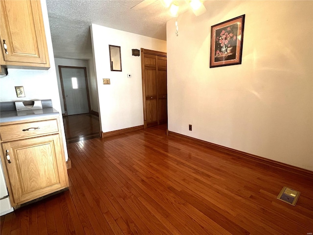 unfurnished dining area with dark wood-style floors, visible vents, ceiling fan, a textured ceiling, and baseboards