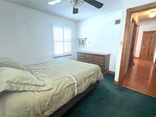 bedroom with visible vents, dark carpet, ceiling fan, a textured ceiling, and baseboards