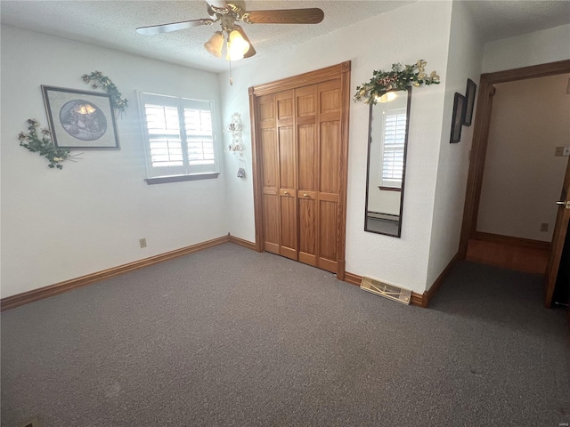 unfurnished bedroom with carpet, a closet, a ceiling fan, a textured ceiling, and baseboards