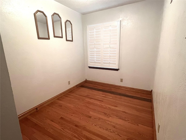 empty room featuring wood finished floors and baseboards