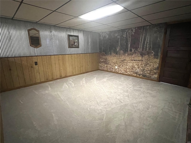 below grade area featuring a drop ceiling, wooden walls, and carpet flooring