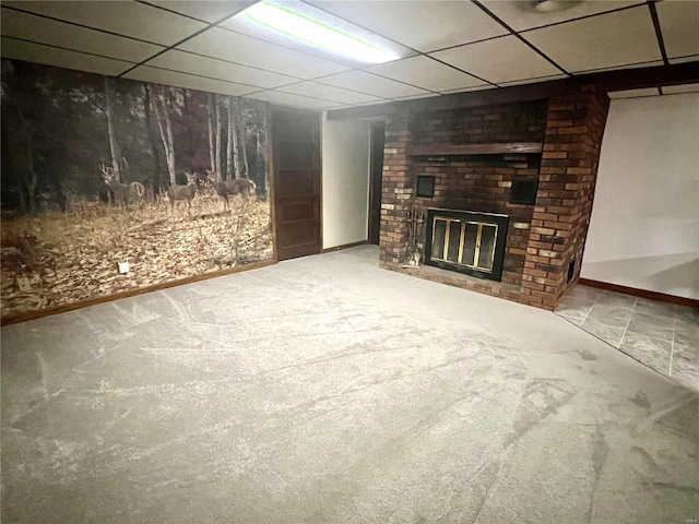 unfurnished living room featuring carpet floors, a fireplace, baseboards, and a drop ceiling