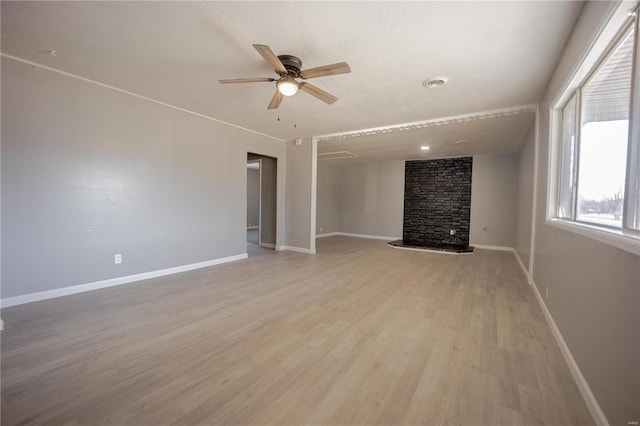 unfurnished living room with baseboards, visible vents, ceiling fan, light wood-type flooring, and a fireplace