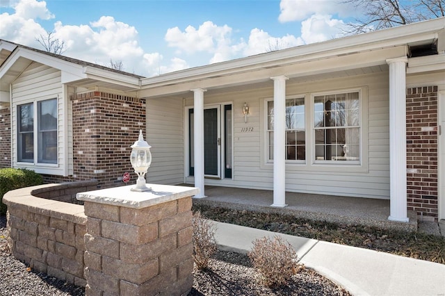 entrance to property with covered porch and brick siding