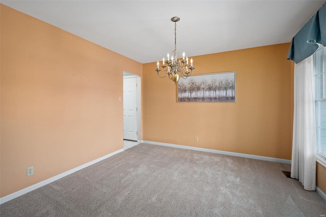 spare room with a chandelier, baseboards, and carpet floors