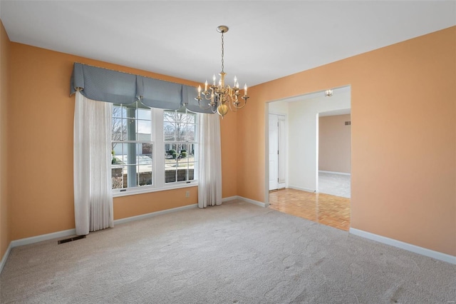 empty room featuring visible vents, a notable chandelier, carpet, and baseboards