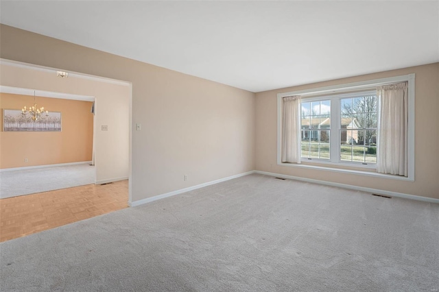 unfurnished room featuring a notable chandelier, visible vents, baseboards, and carpet floors