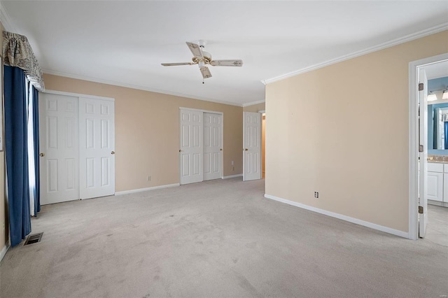 unfurnished bedroom with visible vents, baseboards, two closets, and crown molding