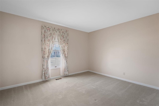 carpeted spare room featuring visible vents and baseboards