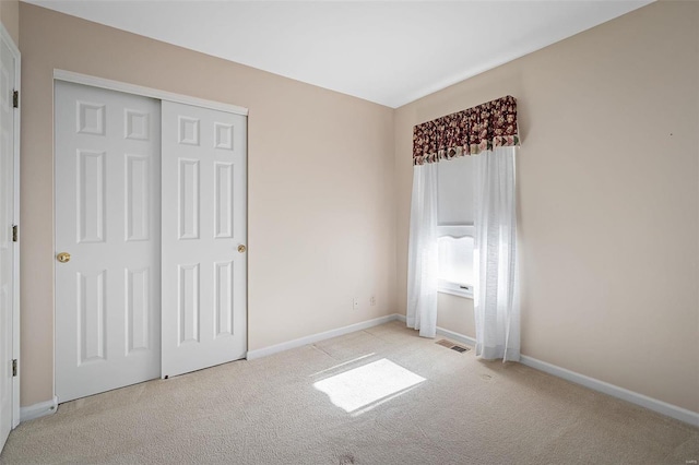 unfurnished bedroom featuring light carpet, visible vents, a closet, and baseboards