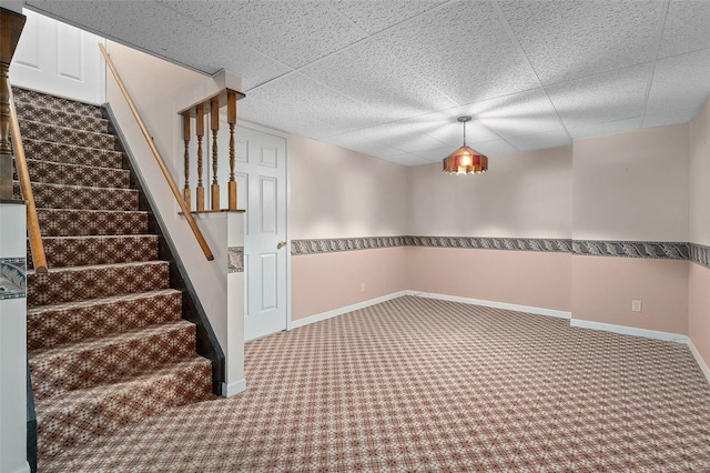 interior space with a drop ceiling, baseboards, and carpet floors