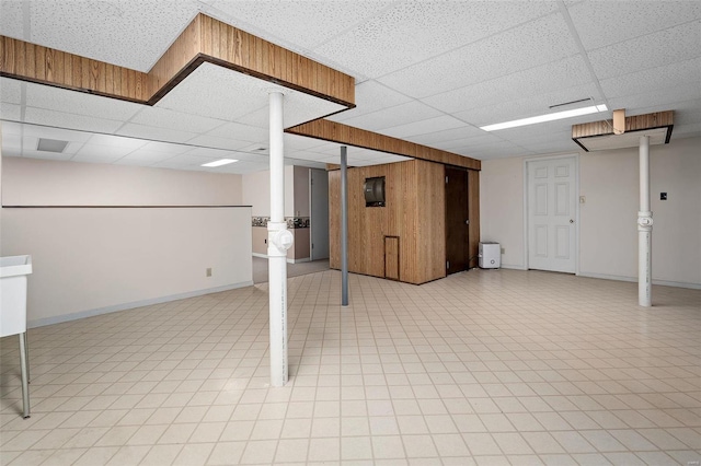 finished basement featuring baseboards and a paneled ceiling