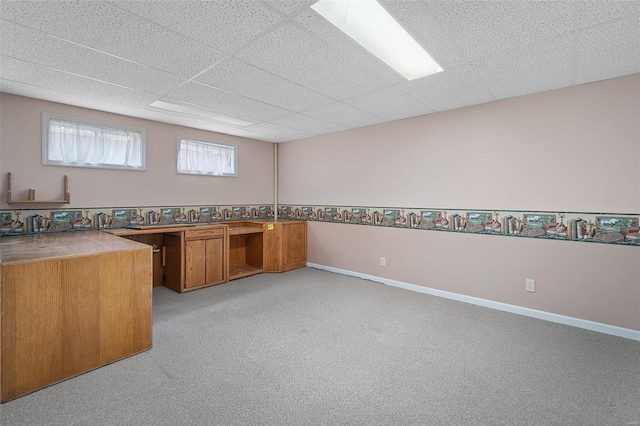 unfurnished office featuring baseboards, a paneled ceiling, and light colored carpet