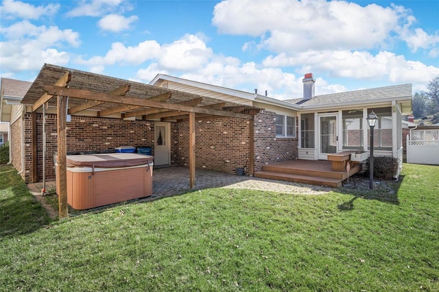 back of property featuring a lawn, brick siding, and a hot tub