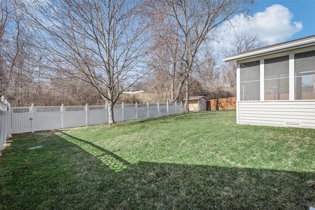 view of yard with an outbuilding, a storage shed, a fenced backyard, and a sunroom