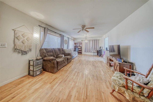 living area with a wealth of natural light, baseboards, a ceiling fan, and wood finished floors