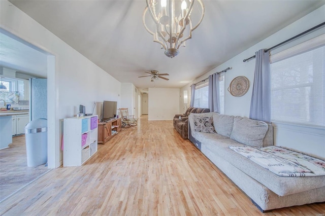 living area featuring ceiling fan with notable chandelier and light wood finished floors