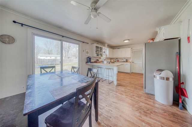 dining area with light wood-type flooring, a ceiling fan, and crown molding