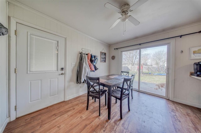 dining area with crown molding, light wood-style flooring, a ceiling fan, and baseboards