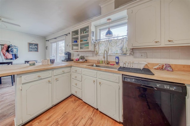 kitchen featuring a sink, tasteful backsplash, light wood-style floors, a peninsula, and dishwasher