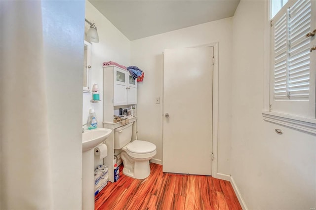 bathroom featuring toilet, wood finished floors, and baseboards