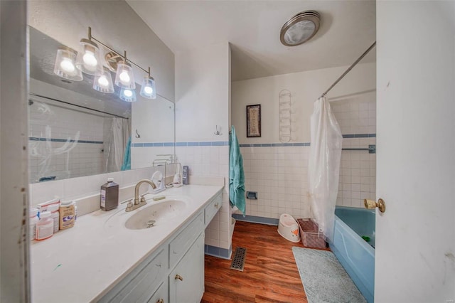 bathroom featuring vanity, wood finished floors, visible vents, shower / bath combination with curtain, and tile walls