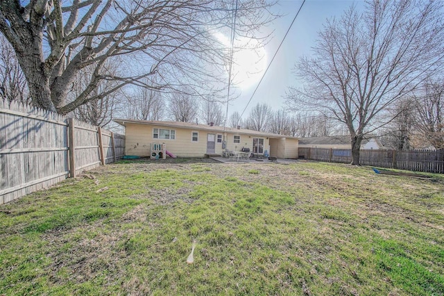 rear view of house featuring a yard, a fenced backyard, and a patio area