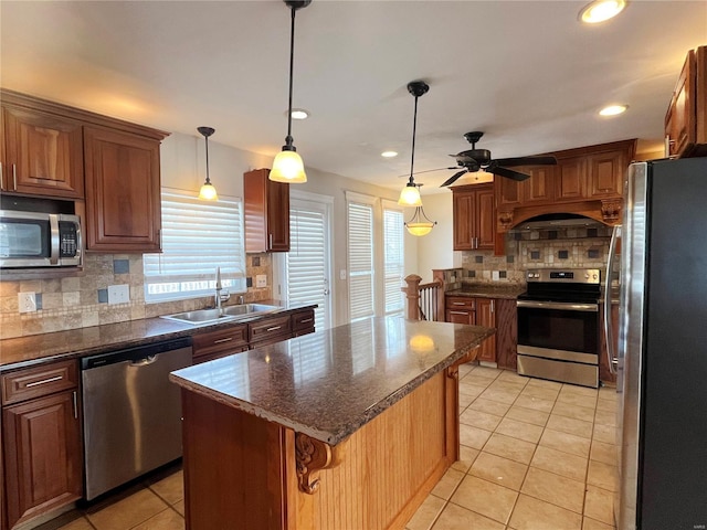 kitchen featuring light tile patterned floors, stainless steel appliances, a kitchen island, and a sink