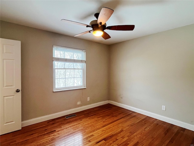 empty room featuring visible vents, ceiling fan, baseboards, and wood finished floors