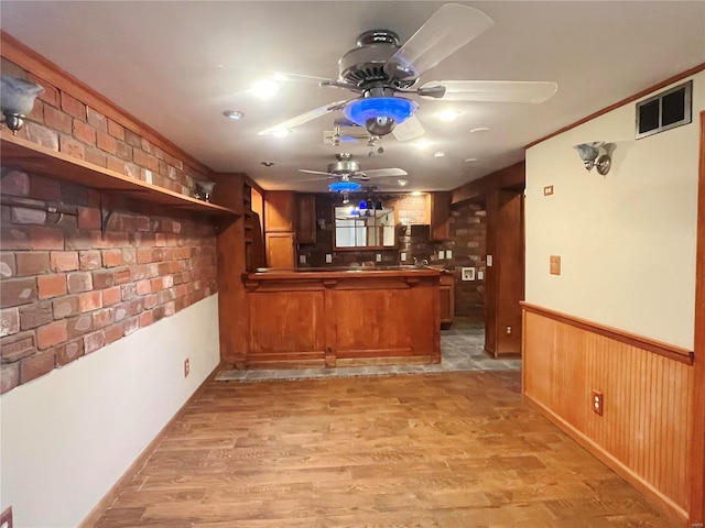 bar with light wood-style flooring, visible vents, bar area, and wainscoting