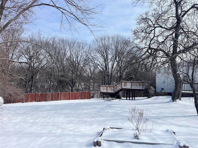 snowy yard with a wooden deck and fence