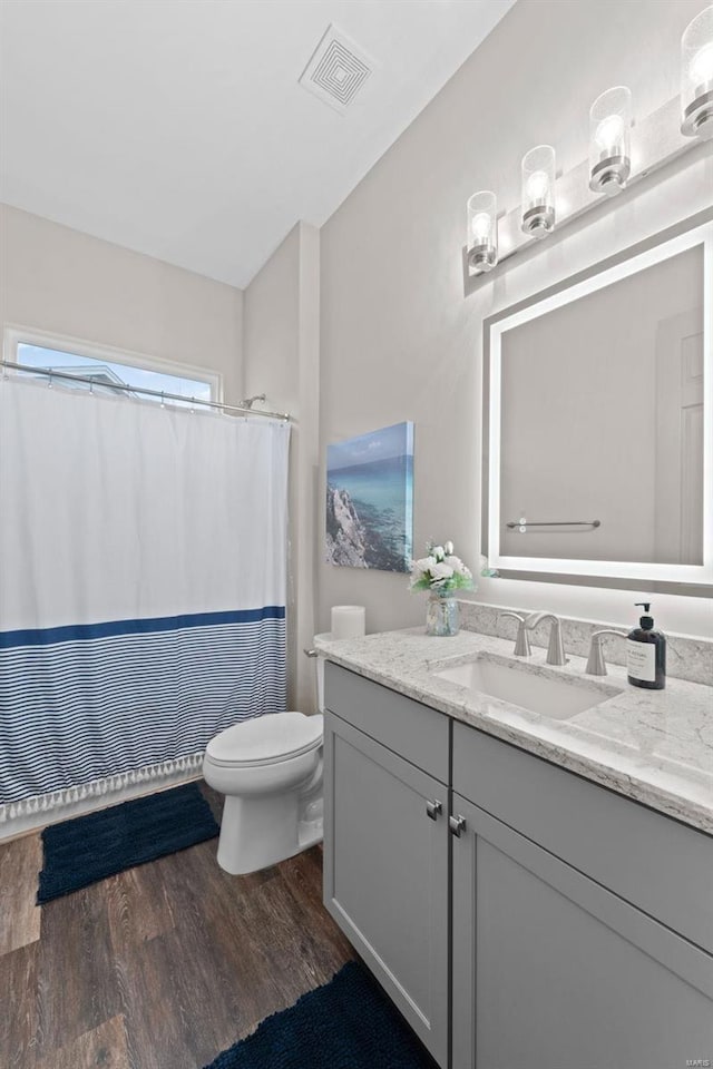 bathroom with visible vents, toilet, a shower with curtain, wood finished floors, and vanity