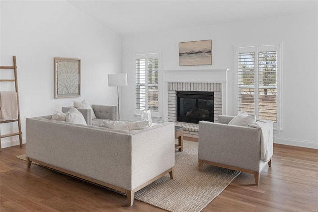 living room with a fireplace, baseboards, and wood finished floors