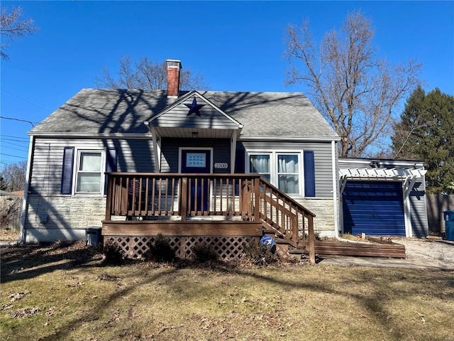 back of property featuring roof with shingles, a yard, a chimney, a garage, and stone siding