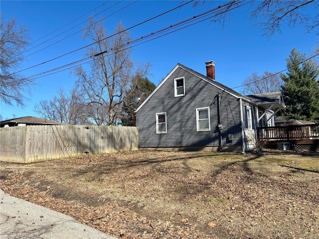 view of side of home with a chimney, fence, and a wooden deck