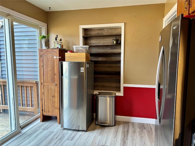 kitchen with light wood-style flooring, baseboards, and freestanding refrigerator