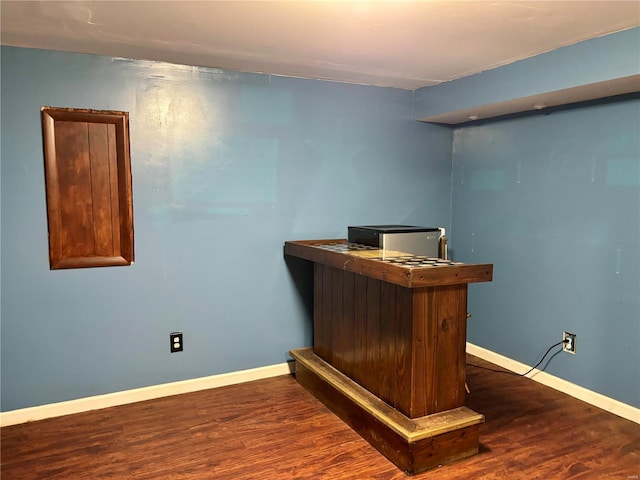 office space with baseboards, a bar, and wood finished floors